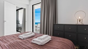 Un dormitorio moderno con una cama grande, un aparador y vistas al océano.