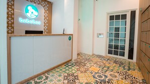 A reception area with a neon sign for 'bobobox', a patterned floor, and a door leading to a room with a view. - Bobopod Kota Lama Semarang (Semarang)