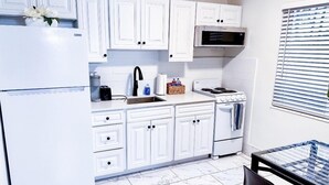 A compact kitchen with white cabinets, a built-in microwave, a stove, and a sink. - Sapphire by the Sea Unit 8 - King Pool View Suite, kitchen, pool view, Sleeps 2 (Fort Lauderdale)