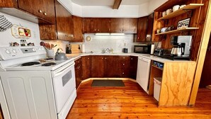 A compact kitchen with wooden cabinets, a white stove, and a coffee machine. - Edge Water Lodge (EV), Waters Edge Lodge (Fremont County)