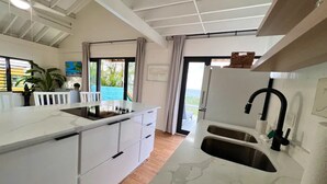 A modern kitchen with white cabinetry, a built-in stove, and a large window offering a view of the outdoors.