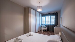 Una habitación de hotel con una cama grande, una silla, una mesita de noche y una ventana con cortinas.