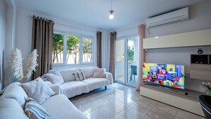 Un salón con sofá, televisión y ventanas amplias.