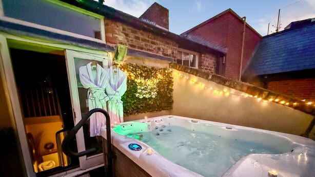A hot tub with a control panel, a chair, and a towel rack. - Chester Apartments (Apt B) (Chester)