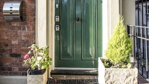 A green double door with a small porch area, a mailbox, and two potted plants. - Chester Apartments (Apt B) (Chester)