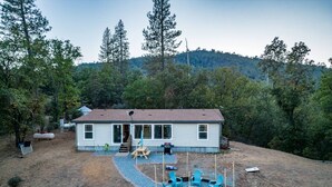 A single-story house with a fenced backyard, a fire pit, and outdoor seating. - GameRoom*HotTub*HomeTheater*EV*Fire pitw/Mtn View (Midpines)