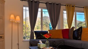 A living room with a sofa, a coffee table with a vase of flowers, and a floor lamp. - GameRoom*HotTub*HomeTheater*EV*Fire pitw/Mtn View (Midpines)