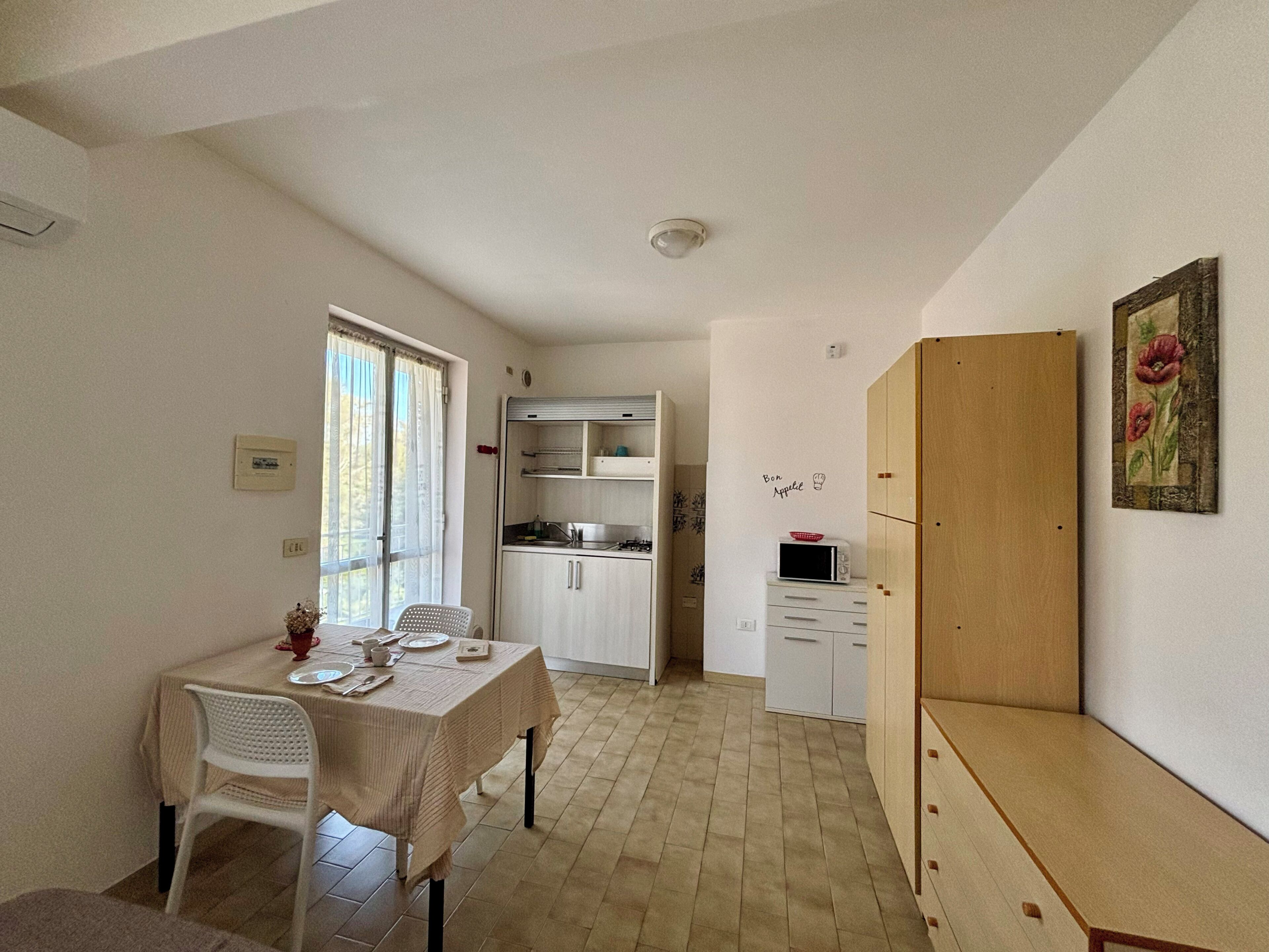A compact kitchen with white cabinets, a microwave, and a wooden cabinet.