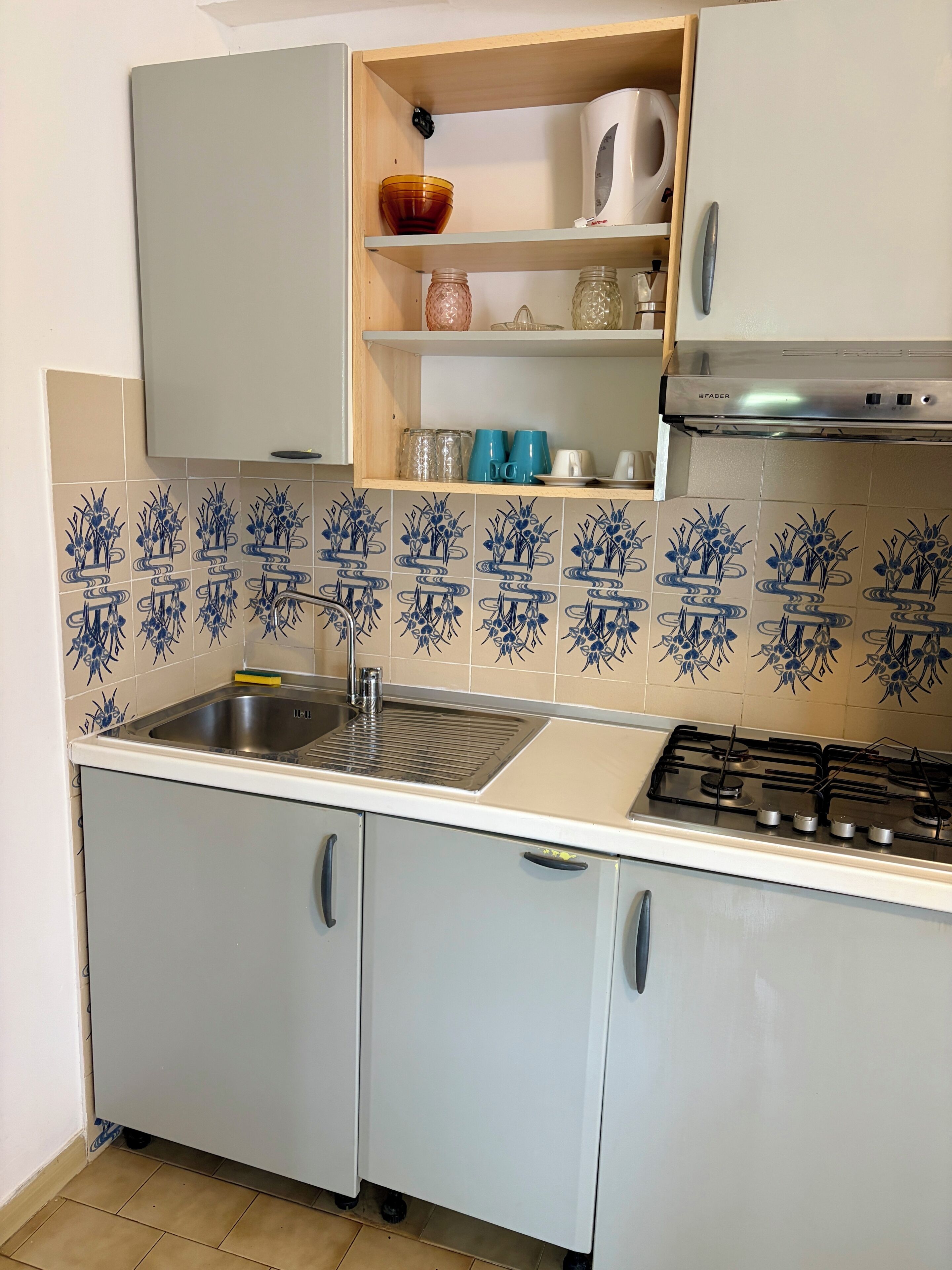 A kitchen with a sink, stove, and cabinets.