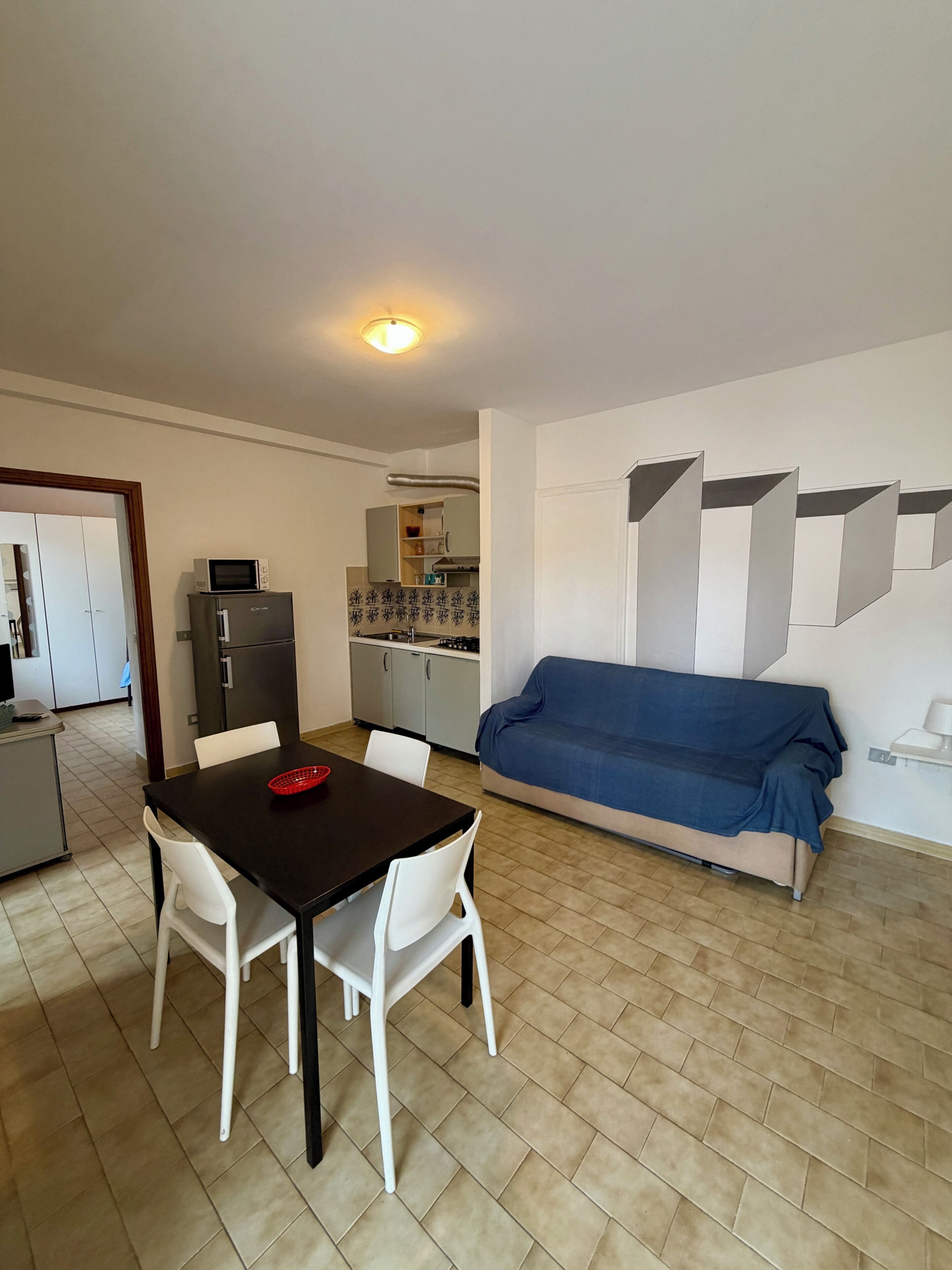 A compact living space with a dining area, kitchenette, and a sofa.