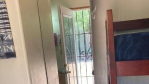 A narrow hallway with a door leading to a balcony with a view of greenery. - Charming Casita in Historic Barrio Viejo 144 sq ft. (Tucson)