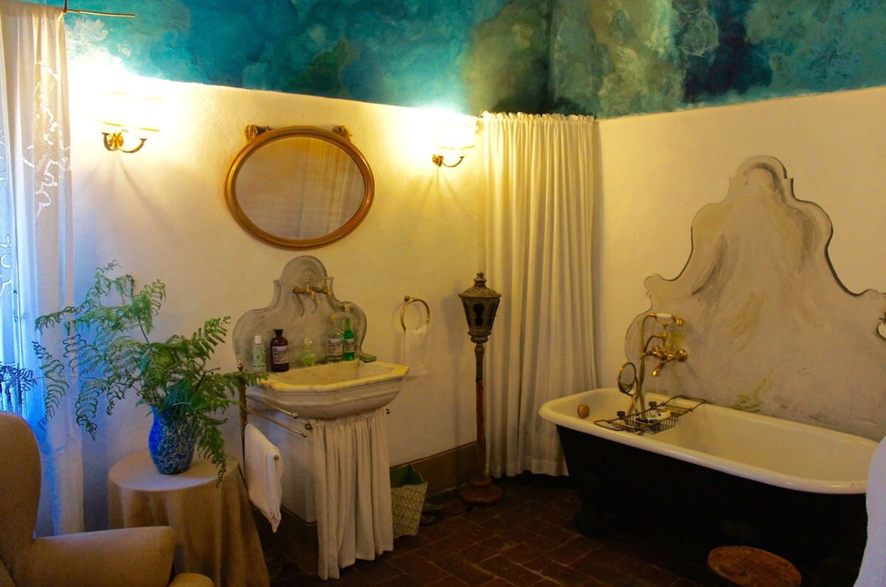A bathroom with a sink, mirror, bathtub, and a potted plant.