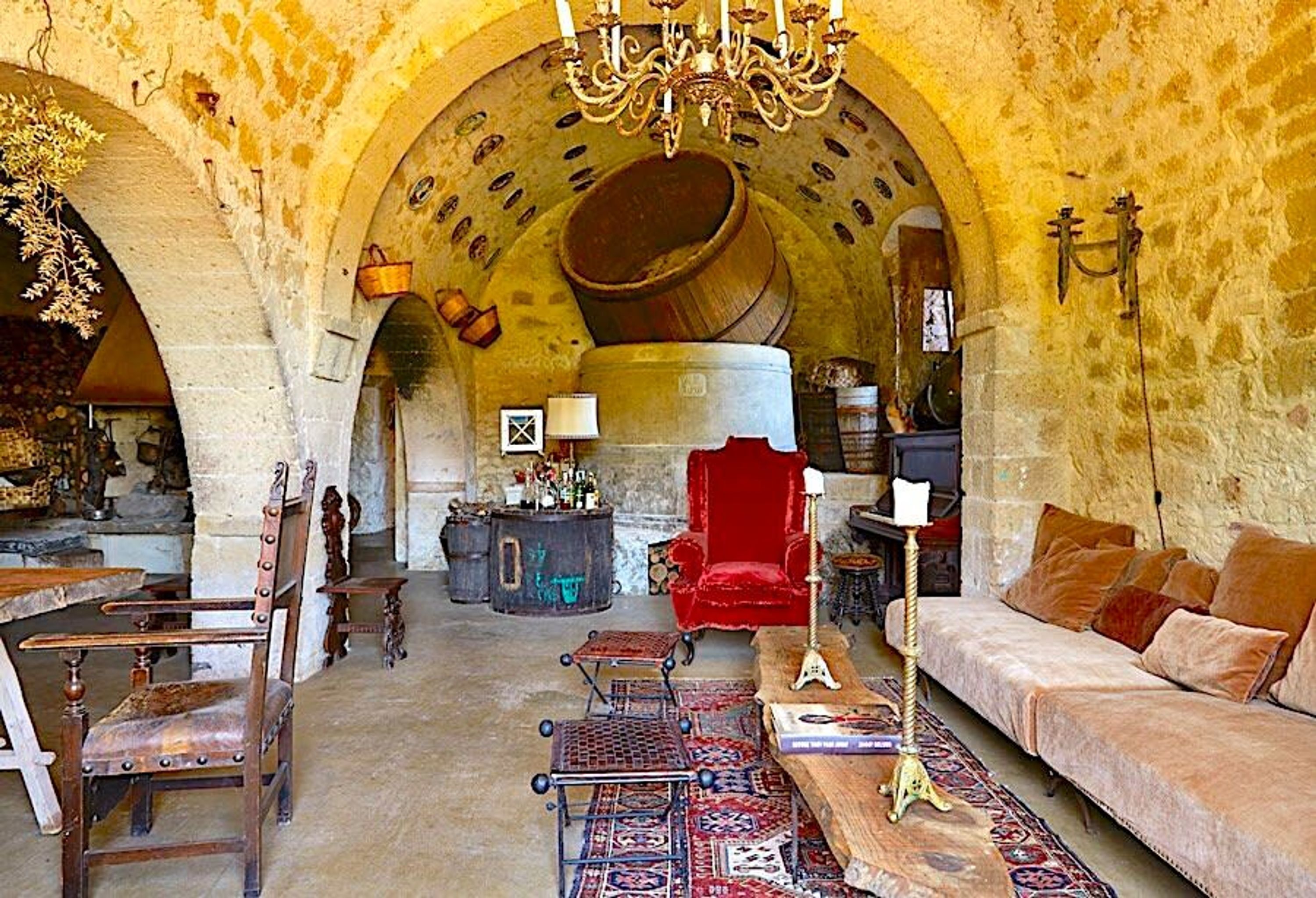 Un intérieur avec un plafond en voûte, un fauteuil rouge, un canapé et un lustre.