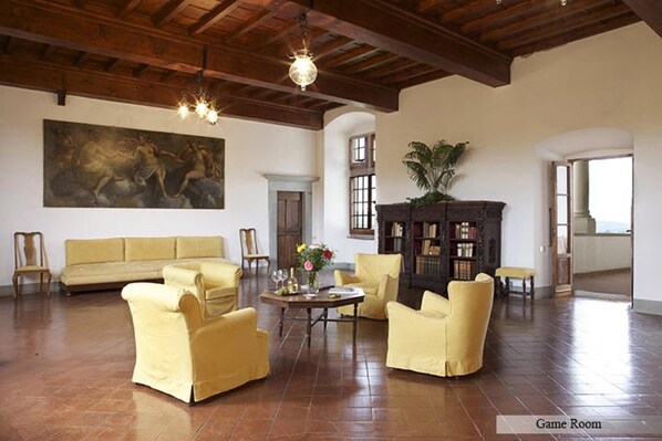 Una habitación amplia con un cuadro grande, un sofá, sillones amarillos, una mesa de centro de madera y una estantería.