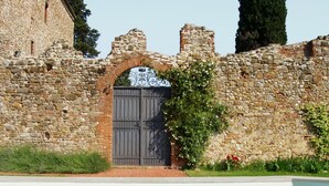 A stone building with a metal gate, a pool, and greenery. - Castello Lorenzo Heart of Tuscany Renaissance Villa With Pool (San Casciano in Val di Pesa)