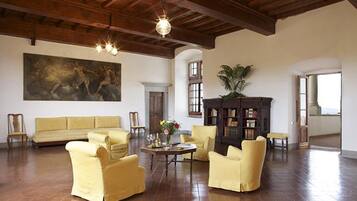 Una habitación amplia con un cuadro grande, un sofá, sillones amarillos, una mesa de centro de madera y una estantería.