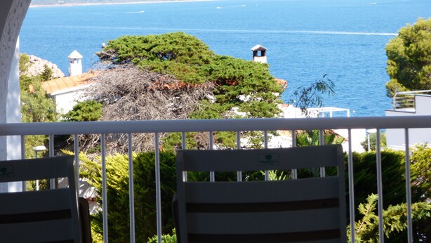 A balcony with a view of the sea, a tree, and a building with a tower. - Magnifica Casa CON Piscina Privada Y Vistas AL MAR (L'Escala)