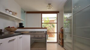 A modern kitchen with white cabinets, a stove, and a large window. - Favoloso - Argentario Tuscany Stunning Modern Seaside Villa Private Pool Access to Sea (Monte Argentario)
