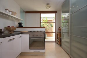 A modern kitchen with white cabinets, a stove, and a large window. - Favoloso - Argentario Tuscany Stunning Modern Seaside Villa Private Pool Access to Sea (Monte Argentario)