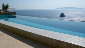 A infinity pool with a view of the sea and a rock formation. - Favoloso - Argentario Tuscany Stunning Modern Seaside Villa Private Pool Access to Sea (Monte Argentario)