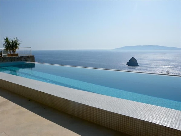 A infinity pool with a view of the sea and a rock formation.
