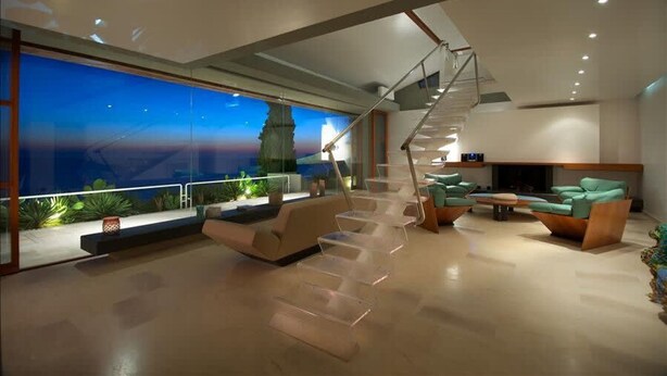 A modern interior with a staircase, seating area, and large windows overlooking a cityscape. - Favoloso - Argentario Tuscany Stunning Modern Seaside Villa Private Pool Access to Sea (Monte Argentario)