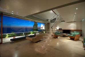 Ein modernes Interieur mit einer Treppe, einer Sitzecke und großen Fenstern mit Blick auf eine Stadtlandschaft.
