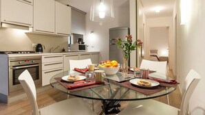 A modern kitchen with white cabinets, a glass dining table, and a hanging pendant light. - In Rome at Spanish Steps Classy Apartment With Modern Design in an Historic Palazzo (Rome)