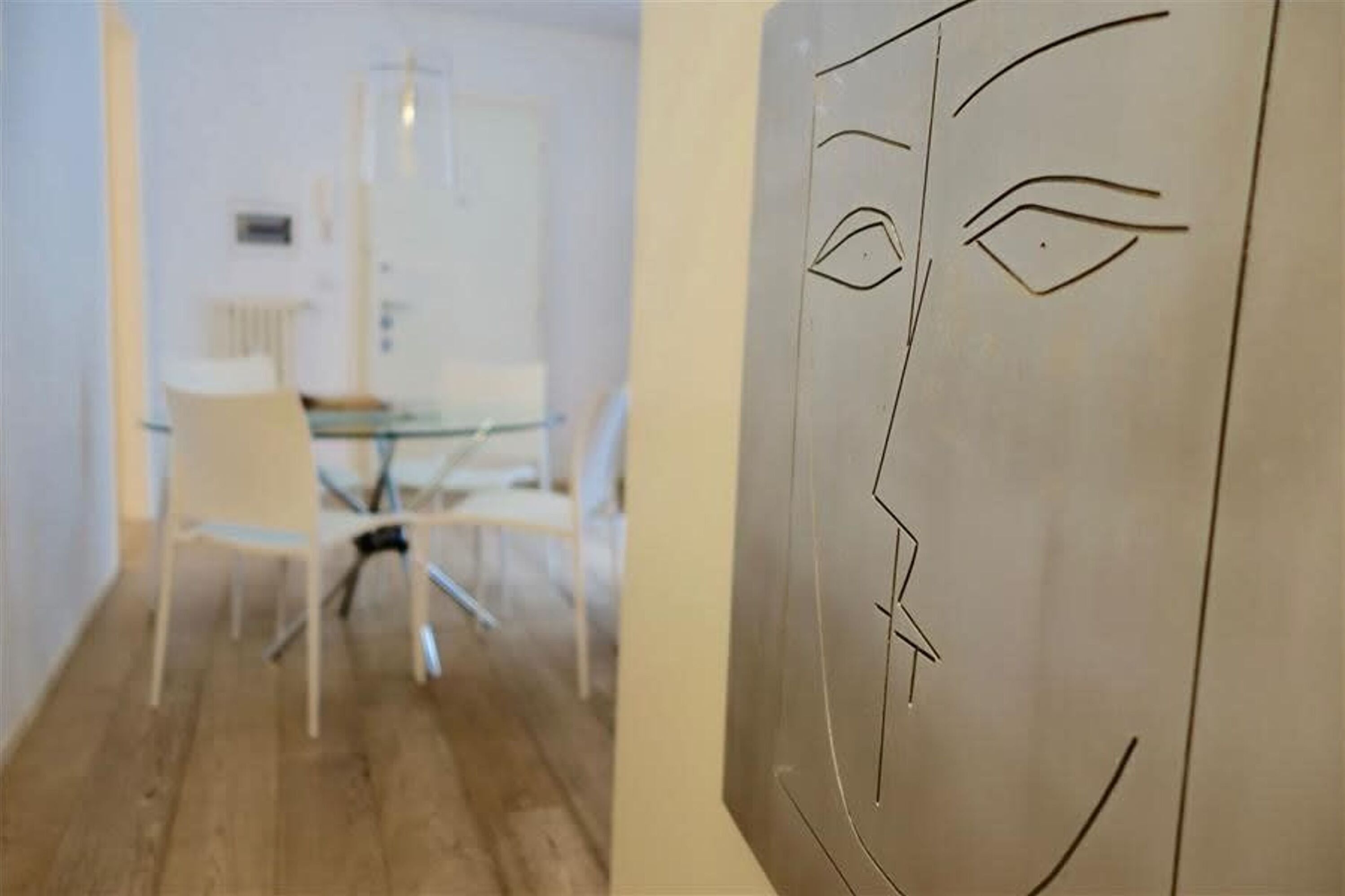 Un intérieur moderne avec un coin repas comprenant une table en verre et des chaises blanches.