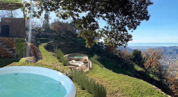 Un bain à remous, un mur de pierre et une vue sur une vallée.