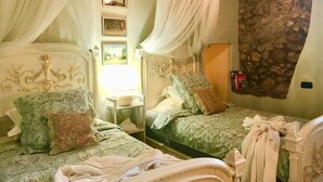 A room with two beds, each with a canopy, a small table, and a mirror. - Sermoneta Historic Stone Village House With Pool in a Medieval Hill Town Close to Rome and Naples (Sermoneta)