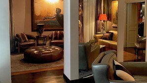 A modern living room with leather sofas, a large painting, and a wooden coffee table. - La Palazzina Santa Dorotea Splendid Rome Townhouse With Courtyard Garden (Rome)
