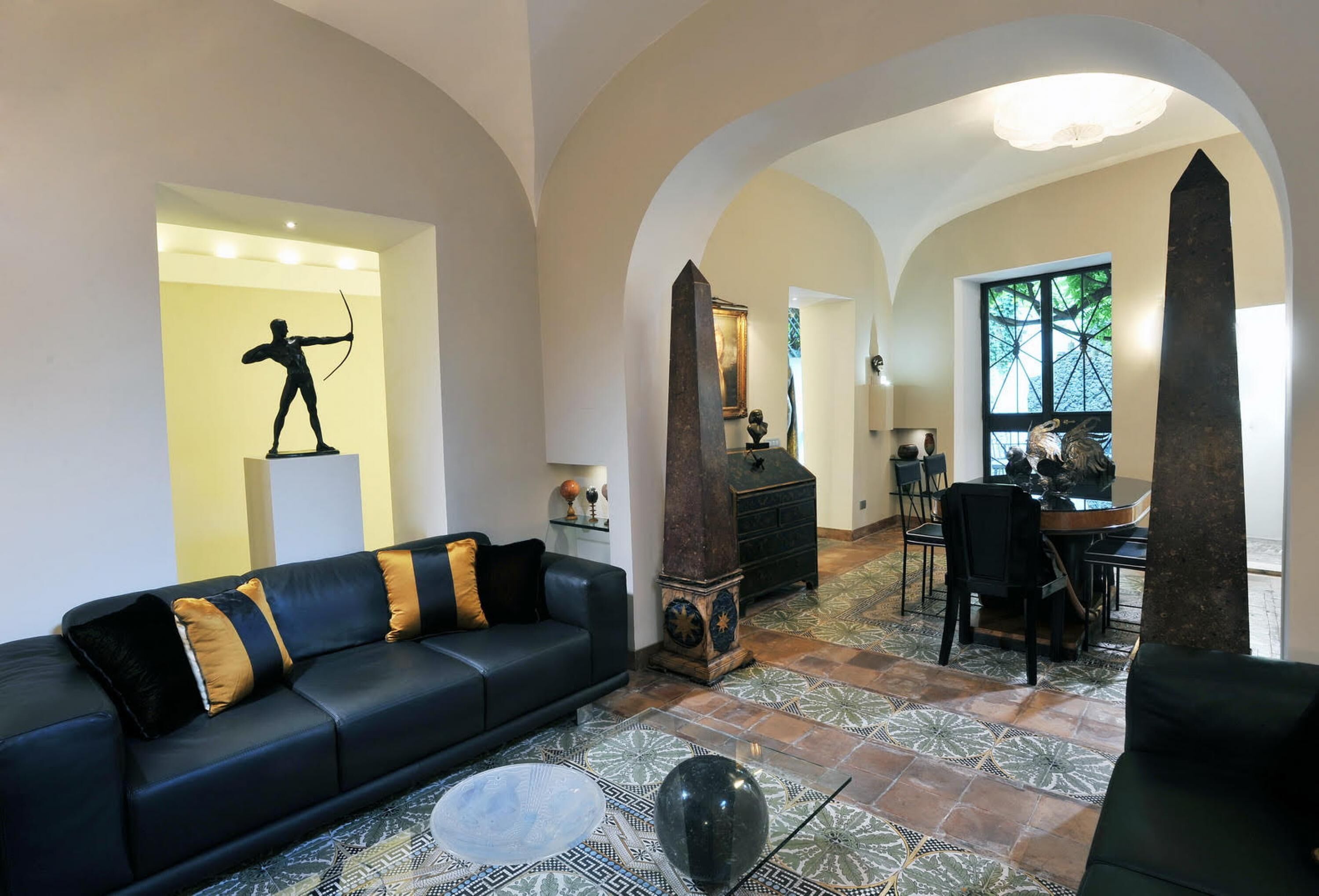 Una sala de estar con un sofá negro, una mesa de centro y una zona de comedor con una mesa y sillas.