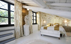 A bedroom with a large bed, a statue, and a view of greenery through the windows. - La Palazzina Santa Dorotea Splendid Rome Townhouse With Courtyard Garden (Rome)