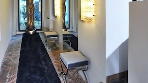 A hallway with a statue, a bench, and a mirror with wall sconces. - La Palazzina Santa Dorotea Splendid Rome Townhouse With Courtyard Garden (Rome)