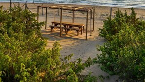 A beach with a wooden bench and a covered seating area.