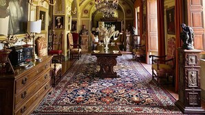 An opulent room with a grand chandelier, ornate ceiling, and a large ornate table with a floral centerpiece.