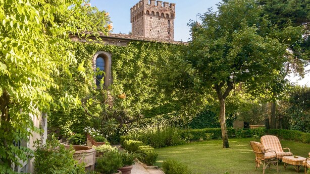 A garden with a stone tower, potted plants, and outdoor furniture.
