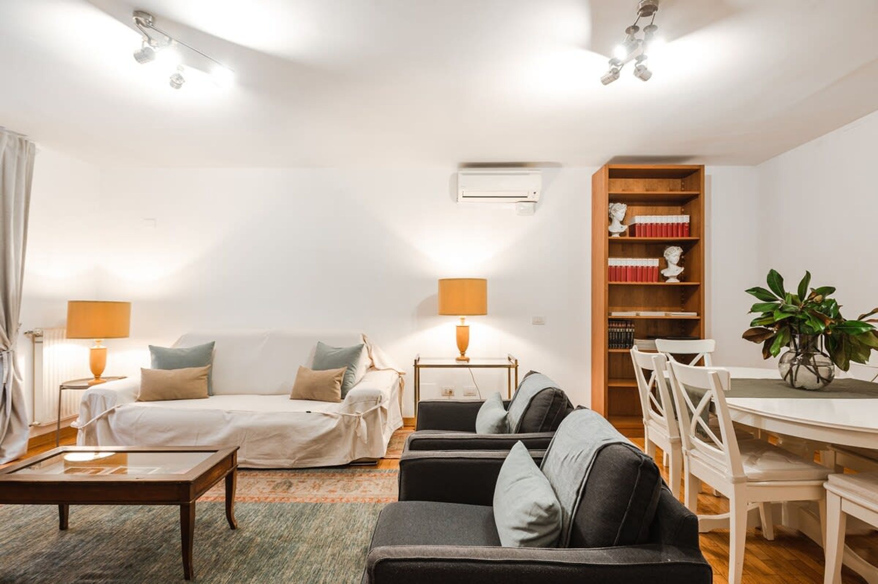 A modern living room with a sofa, a dining table, and a bookshelf.