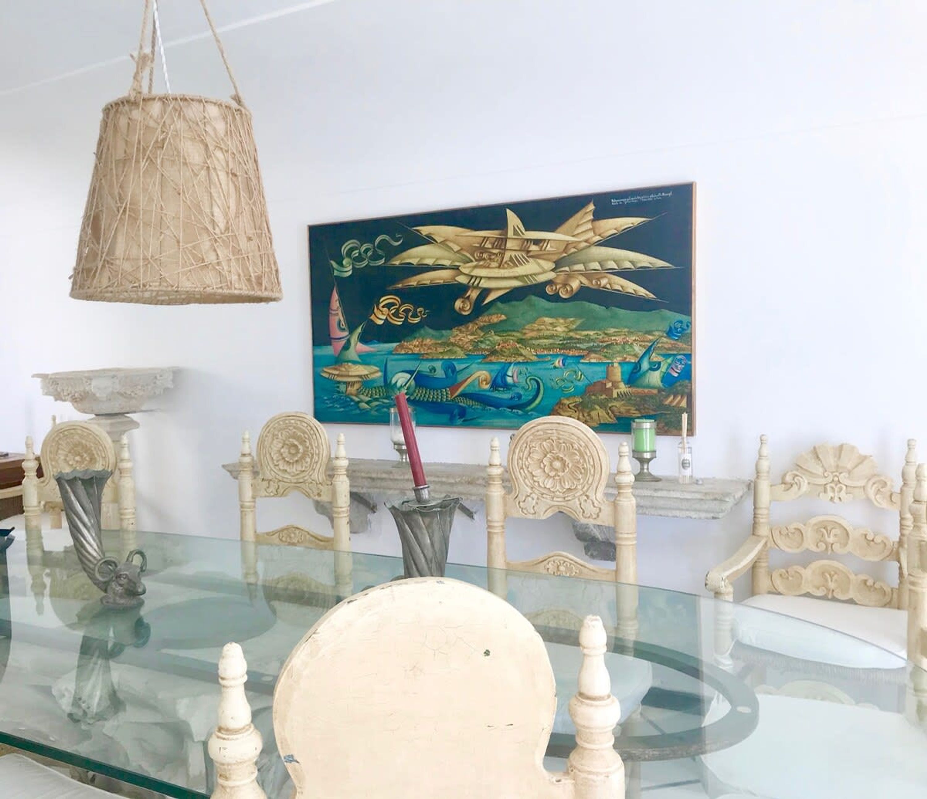 Une table à manger avec des chaises, un luminaire suspendu et un tableau au mur.