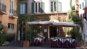 Ein Innenhof mit Sitzgelegenheiten im Freien, einem Restaurantschild und einem Gebäude mit Balkonen.