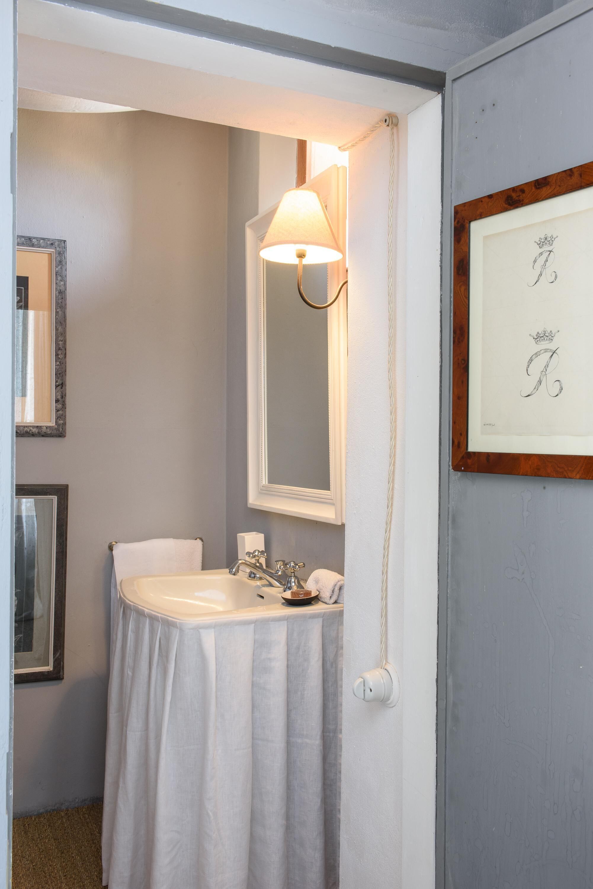 A bathroom with a white sink, a mirror, and a framed picture on the wall.