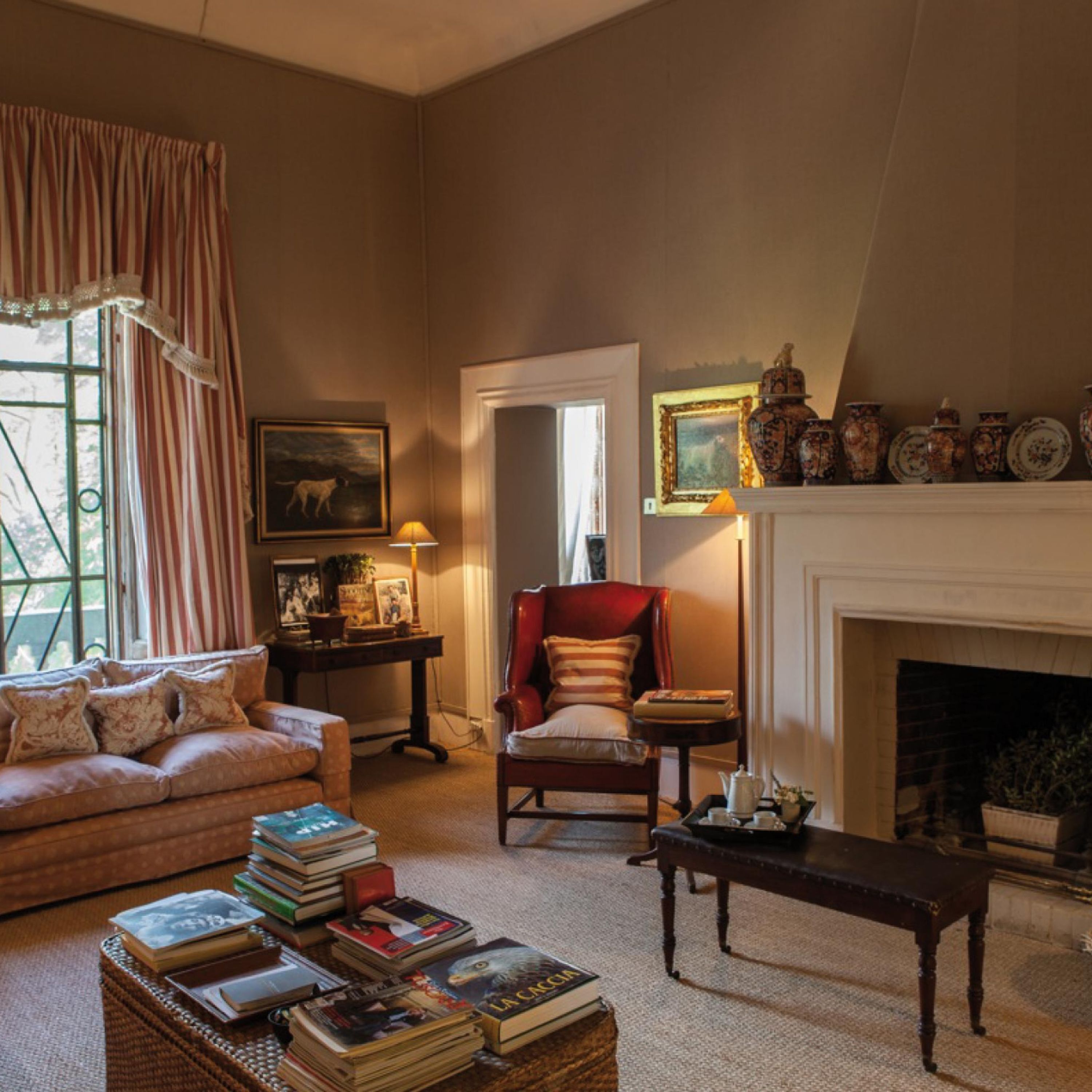 A cozy living room with a fireplace, a sofa, a chair, and a table with books.