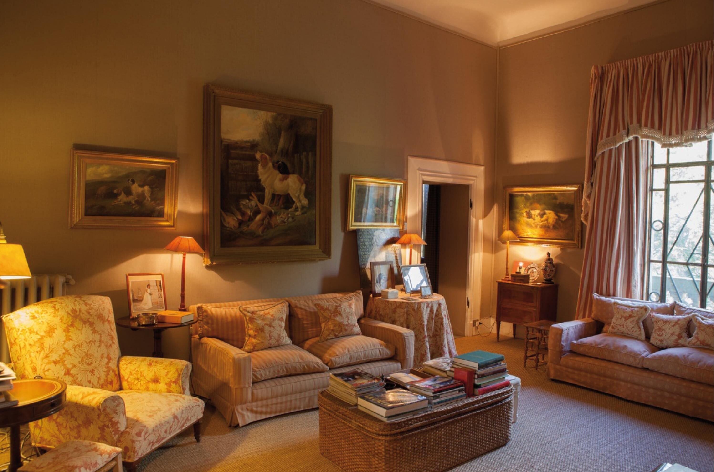 Een gezellige woonkamer met een zithoek, een bijzettafeltje met boeken en kunstwerken aan de muren.