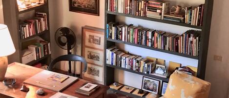 A cozy reading nook with a wooden desk, a chair, and a bookshelf filled with books.
