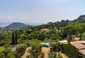 Una villa con piscina rodeada de abundante vegetación y vista al mar.
