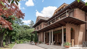 A two-story building with a brick facade, a covered porch with columns, and a garden with potted plants. - Near Rome Villa Pool Tennis Courts Perfect Family Reunion or Off-site Meeting (Grottaferrata)