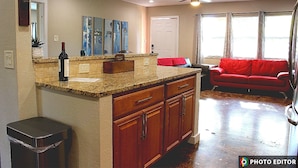 A kitchen with granite countertops, wooden cabinets, and a red couch in the living area. - Relax & Explore – Sarasota Beaches & Downtown! (Sarasota)