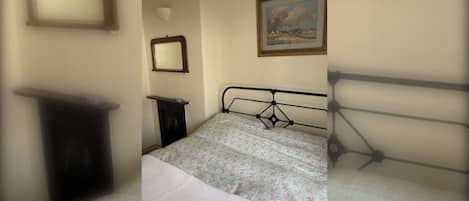 A bedroom with a bed, a nightstand, a dresser, a mirror, and a framed picture on the wall.