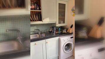 A kitchen with a washing machine, a sink, and a countertop with various items.